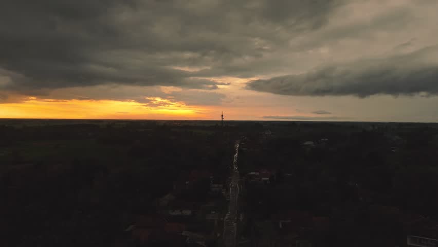A dark landscape photo with a road and sunset