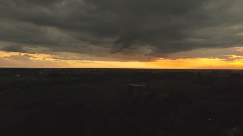 A dark landscape photo with ominous clouds and sunset