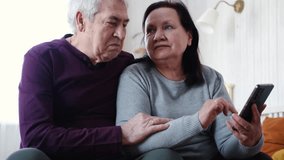 Old couple using a phone together while relaxing in the kitchen at home. Elderly man and woman spending leisure time browsing online with a smartphone. Happy senior married couple typing, learning - Powered by Shutterstock - Get 15% off with code: PIKWIZARD15