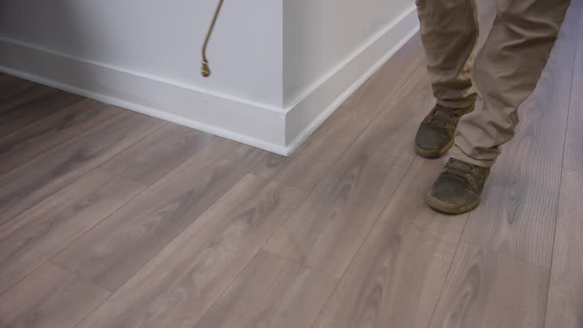 Tracking shot of pest control application being applied indoors along office baseboards and flooring.