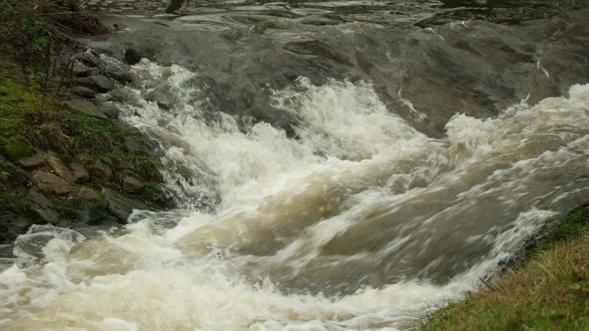 Turbulent river with white water rapids flowing quickly through a narrow rocky channel