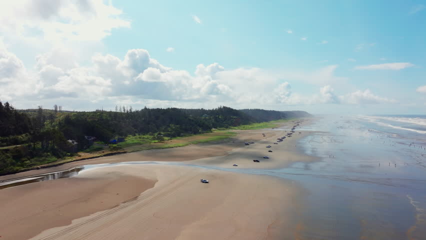 Aerial drone view of Seabrook, Washington, showing beach, Pacific Ocean waves, and coastal shoreline. Dynamic seaside scenery ideal for travel, nature, and ocean footage.