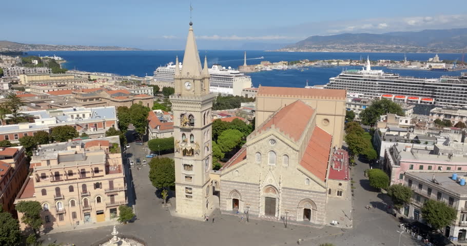 Aerial view of the Cathedral Basilica of Santa Maria, located in the historic center of Messina, Sicily, Italy. The Calabrian coast, separated by the Strait of Messina, is silhouetted on the horizon.