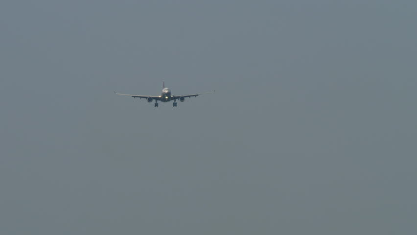 Front view of a passenger jet with no visible airline branding on final approach for landing over the city