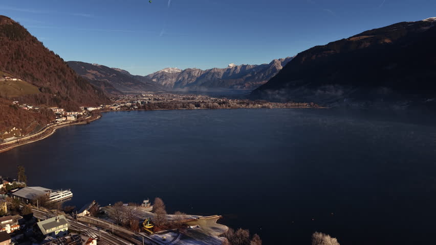 clear blue lake with mountain panorama and sparkling water, aerial view shows calm shoreline and distant ridges, travel blogger