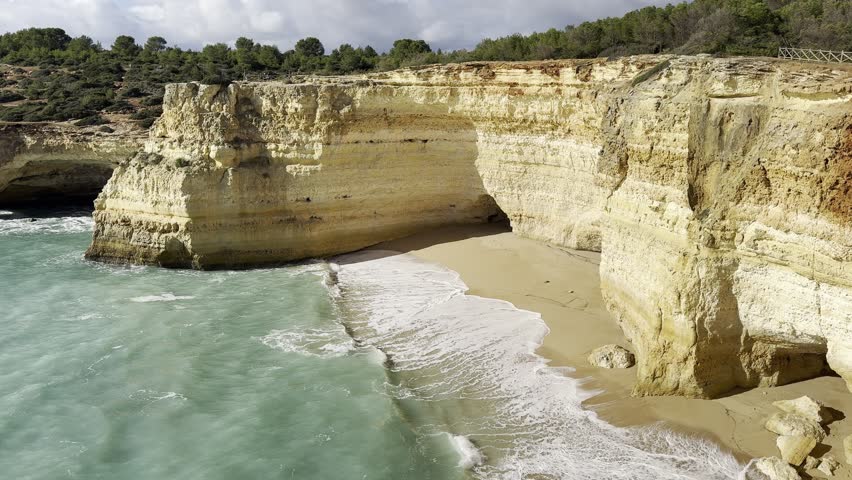 Golden rock cliffs at the coastline of the Atlantic Ocean with beach Praia da Corredoura near the Cave of Benagil, Algarve, Portugal