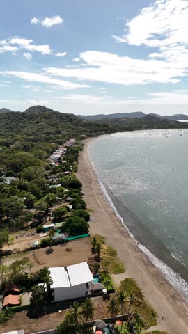 Aerial beach front homes overlooking sandy beach with breaking waves in Potrero Costa Rica.
