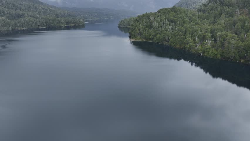 Aerial ascending shot showing Lake Correntoso surrounded by dense green vegetation in the Patagonia region of Argentina