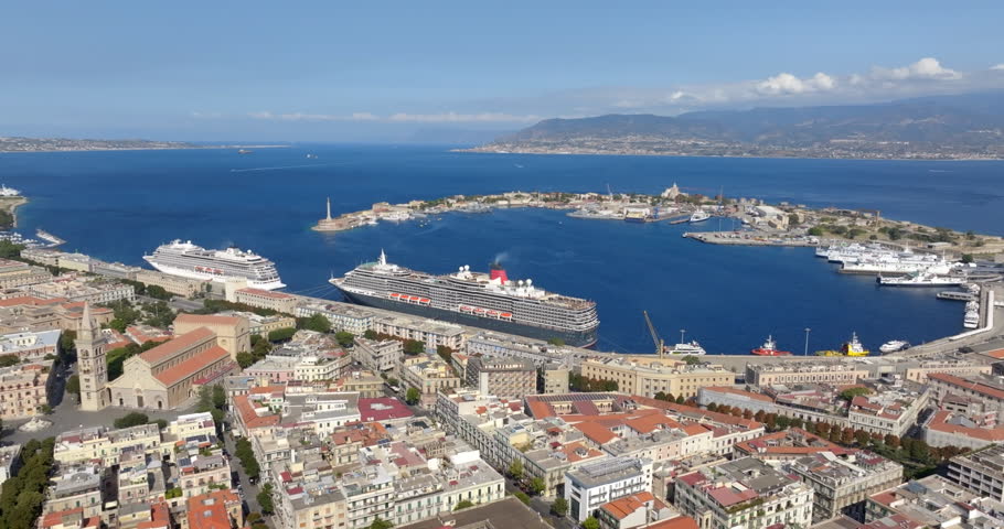 Aerial view of the city port of Messina, Sicily, Italy. Panorama of a crescent-shaped natural harbor. A large cruise ship and various vessels are docked along the quay.The city center is in foreground