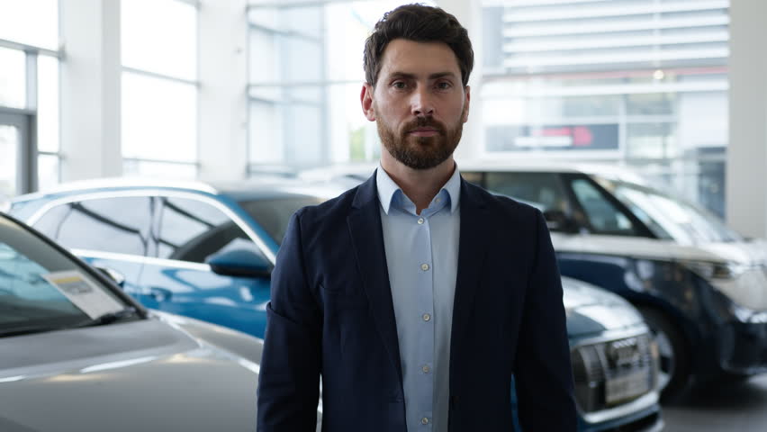 Proud successful Caucasian business man smiling in car dealership showroom arms crossed male confident consultant businessman guy buyer client posing new automobile rent service auto sales transport