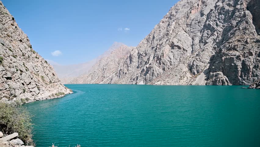A real time view of ripples on the blue water of Hazorchashma Lake, the seventh lake of the Seven Lakes in the Fann Mountains near Panjakent, Tajikistan, with rocky slopes nearby.