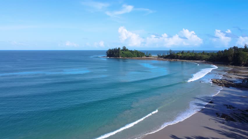 Wide drone footage of a quiet tropical beach in Sabah, Borneo, Malaysia, with turquoise water, sandy shoreline, and coastal vegetation.