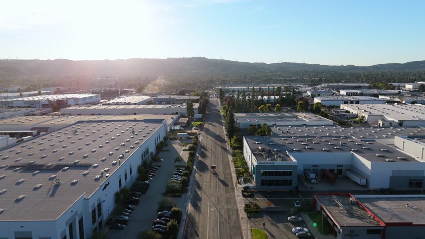 Aerial view of industrial warehouse district with road at sunset