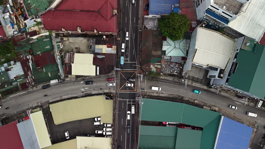 Cinematic slow-motion aerial footage filmed directly overhead showcasing a bustling urban crossroads in Makati center, Manila, Luzon, Philippines. The bird