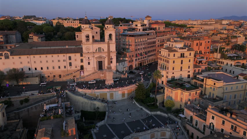 Cinematic aerial view of Piazza di Spagna in Rome Italy with Spanish Steps, historic buildings, warm sunset light and busy urban life creating an iconic European travel scene.