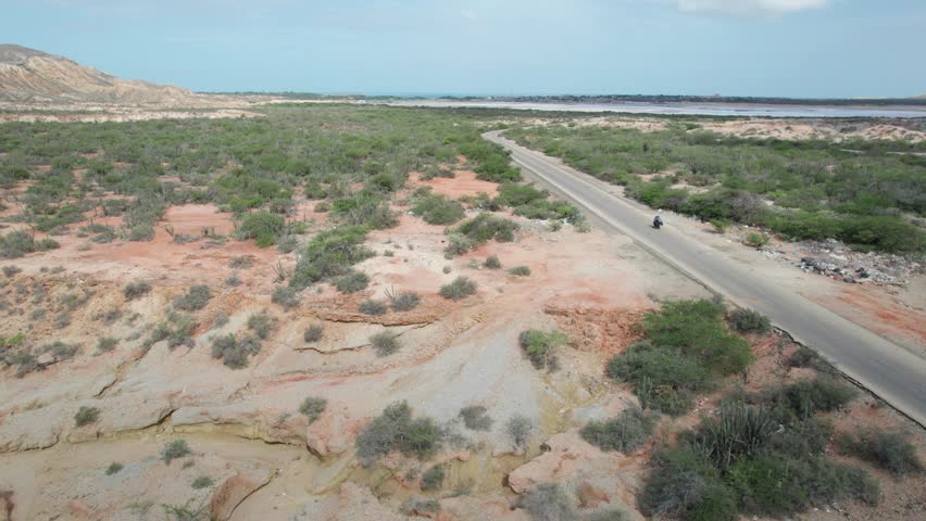 Aerial view tracking motorcycle on desert road Araya Peninsula