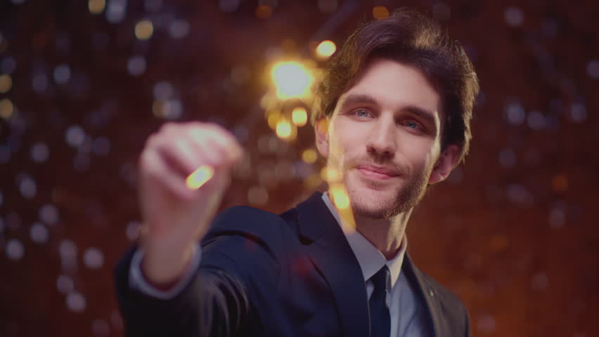 Handsome european man in suit holding sparkler light, enjoying a party or Christmas. Caucasian male burns Bengal fire, smiling and looking on camera. Special occasion and festive mood. Celebrating