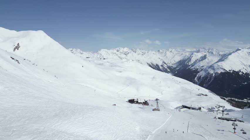 A ski slope with snow covered mountains in the background.