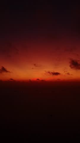 Majestic sunset over ocean horizon with silhouetted boats and vibrant colors.