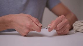 Closeup hands assembling ethernet connector on white table using pliers to strip and crimp cable coil visible calm studio lighting network installation demonstration - Powered by Shutterstock - Get 15% off with code: PIKWIZARD15
