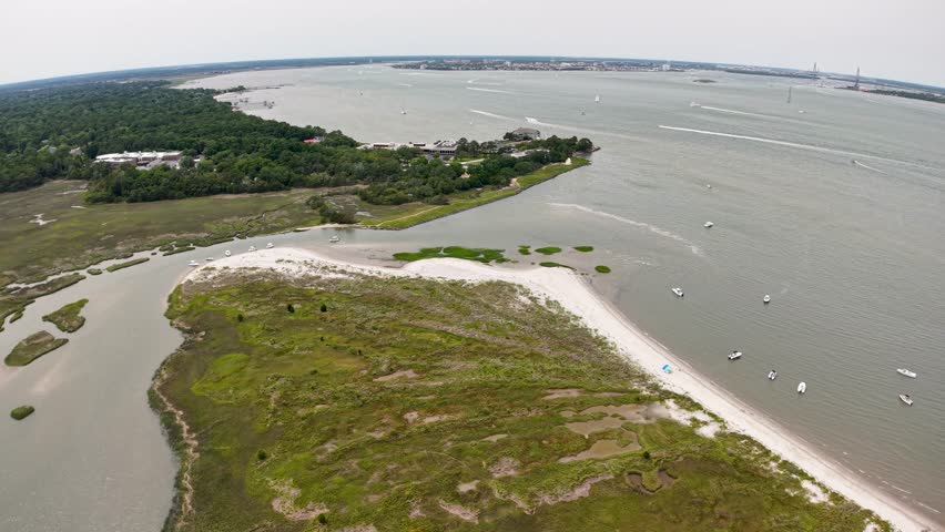Aerial drone view of a sandy peninsula extending into a wide river or tidal estuary at Middleton Place Plantation near Charleston, South Carolina, bordered by calm waters and lush greenery.