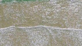 Bird's eye perspective of gentle ocean waves and white foam rolling onto a sandy beach. - Powered by Shutterstock - Get 15% off with code: PIKWIZARD15