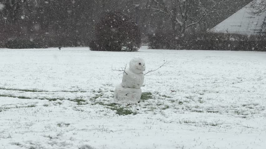 Winter fun outdoors: A small snowman with twigs for arms in a park landscape