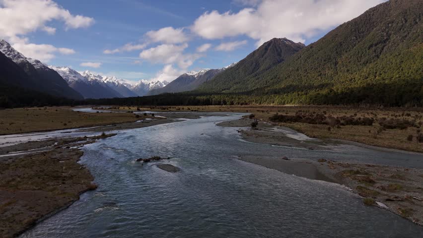 Low Flight Over Creek Between Snowy Mountains Covered With White Clouds Way to Milford Sound, Southland, New Zealand