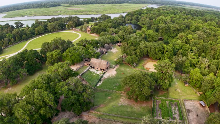 An aerial drone video shows the historic Middleton Place estate near Charleston, South Carolina, with a circular lawn and curved driveway, surrounded by lush trees and overlooking a winding river.