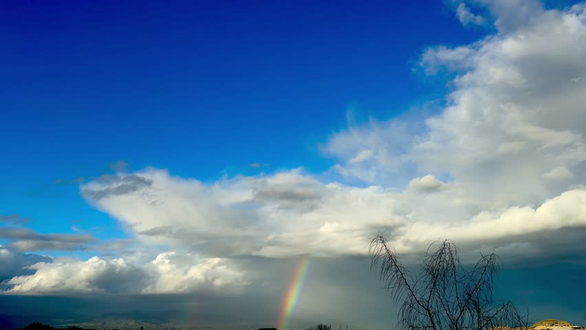 Rainbow over landscape. Rainbow over landscape under cloudy sky.