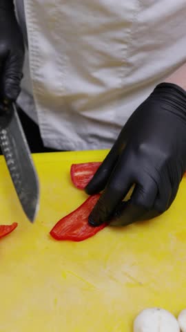 Chef cutting red chili pepper in restaurant kitchen