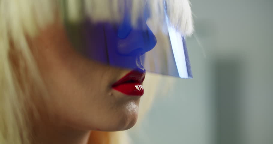 A close-up shot of a woman wearing a futuristic blue visor and vibrant red lipstick in soft lighting stunning visuals atmospheric lighting rich detail