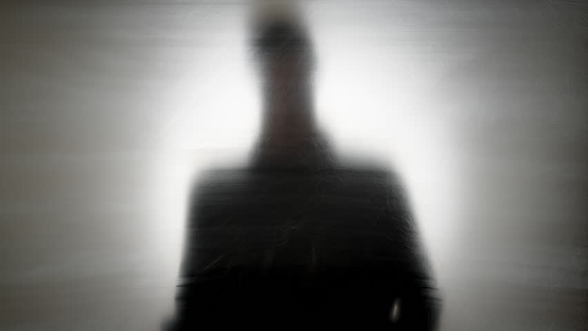 Blurred silhouette of a man sitting alone, reflecting on mental health, stress, or anxiety, evoking emotions of isolation and contemplation.
