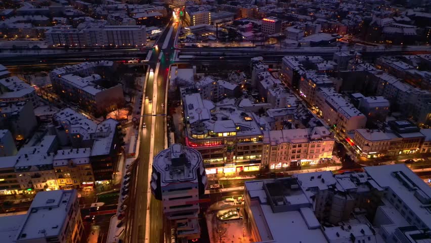 urban shopping street architecture and illuminated streets of Berlin Steglitz district covered in fresh snow during snowy winter evening. Wonderful aerial view drone camera pointing down