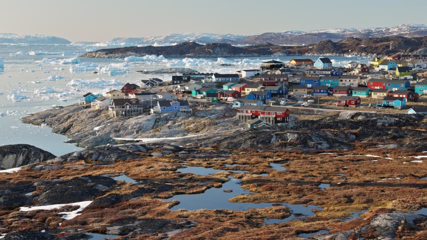 Pan shot of Ilulissat town in Greenland, Arctic coastal city with colorful houses and cold northern atmosphere