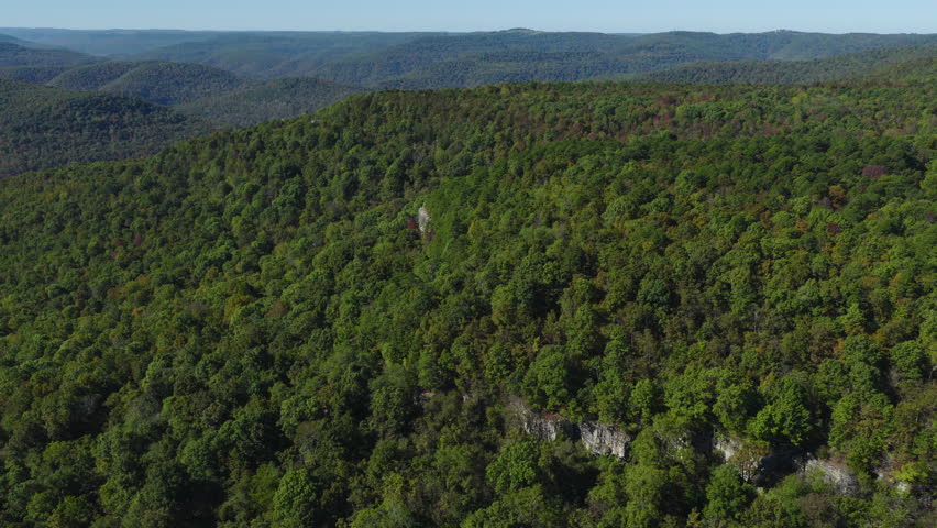 Drone glides above continuous hardwood canopy revealing layered ridges and valleys of the Ozark Mountains, Antenna Pine Arkansas
