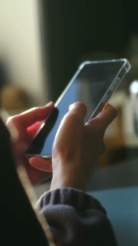 Hands tap phone, Closeup of hands engaging with smartphone, Focus on fingers touching phone under gentle interior lighting, Detailed view of hands swiftly navigating smartphone in modern setting