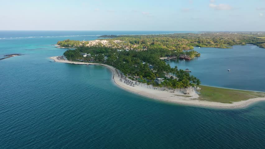 Drone overhead view of the beach of Constance Belle Mare Plage in Mauritius, with palm trees, umbrellas and a beautiful turquoise sea with transparent water. Luxury 5 star hotel in Mauritius.