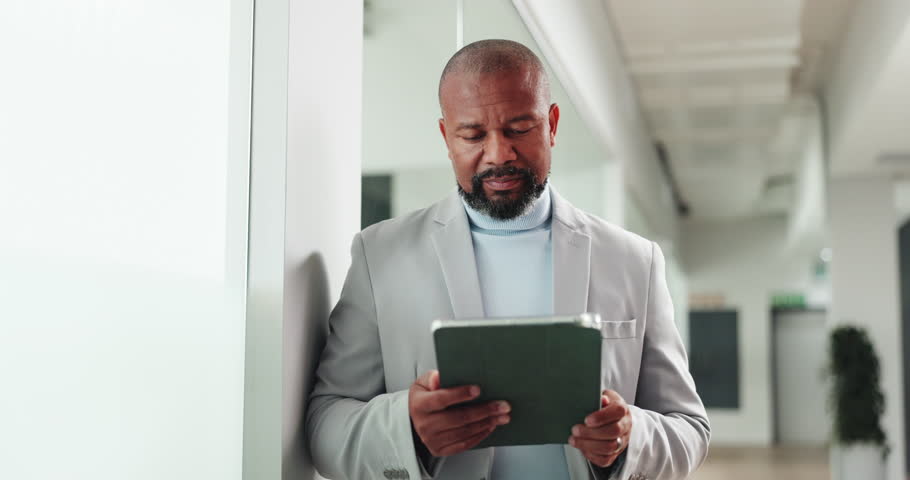 Mature man, tablet and thinking at office, window and check notification with real estate deal. African person, realtor and property developer with tech, app and decision for proposal in corridor