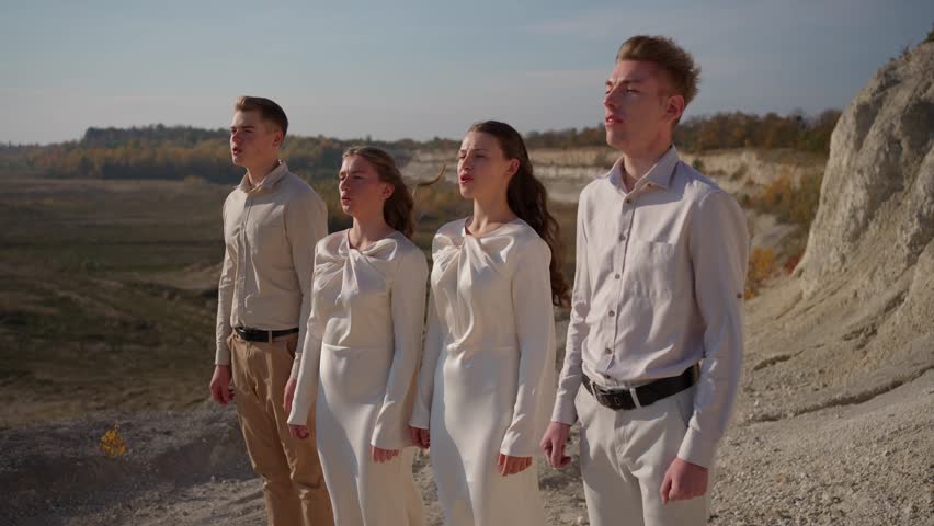 Young vocal ensemble singing together and standing on rocky landscape. Singing group concept.