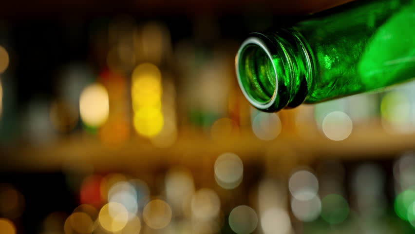 Pouring Beer from Bottle . Stream of Golden Carbonated Liquid Flows in Slow Motion on a Pub . Filmed on High Speed Cinematic Camera at 1000 FPS