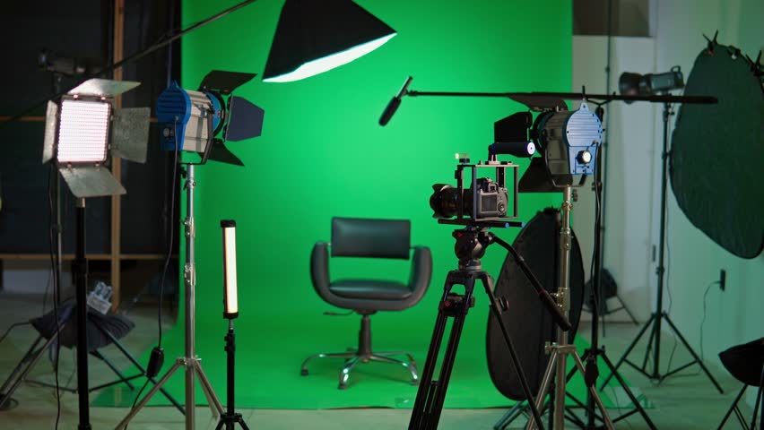Empty chair on a film set with professional camera, lighting, and a green screen background