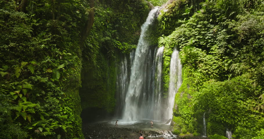 Sendang Gile Waterfall water cascading in natural pool, tourists people enjoy swimming, relax and exploring the lush green jungle environment on Lombok tropical island, Indonesia. Aerial view panorama