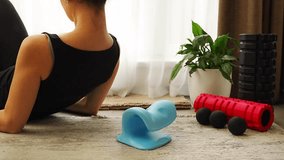 Young woman lies on the floor using a blue cervical traction device to stretch the neck. Home therapy for neck pain, muscle tension and spine decompression - Powered by Shutterstock - Get 15% off with code: PIKWIZARD15