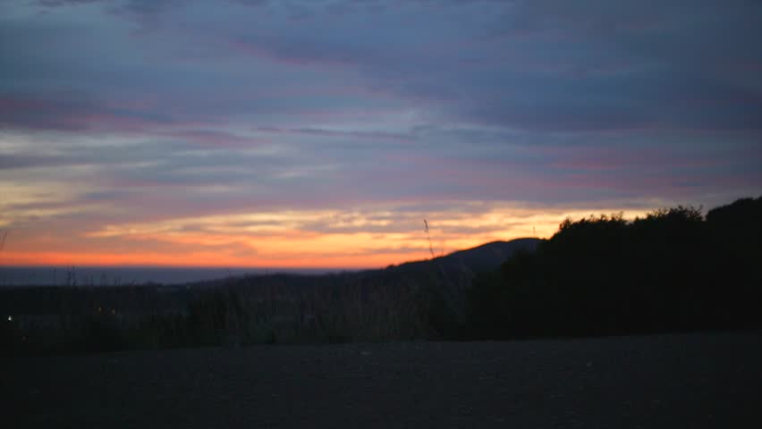 A woman contemplates the beautiful sunset landscape from the top of the mountain.