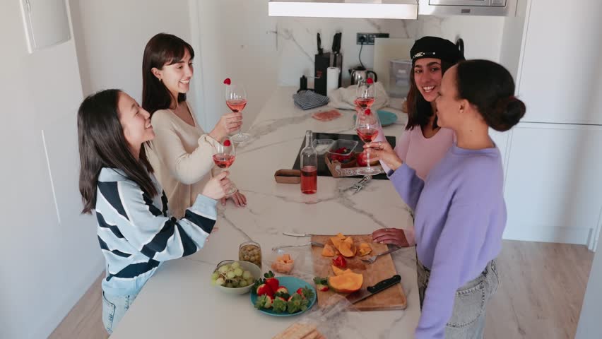 Group of four female friends smiling and clinking glasses over table