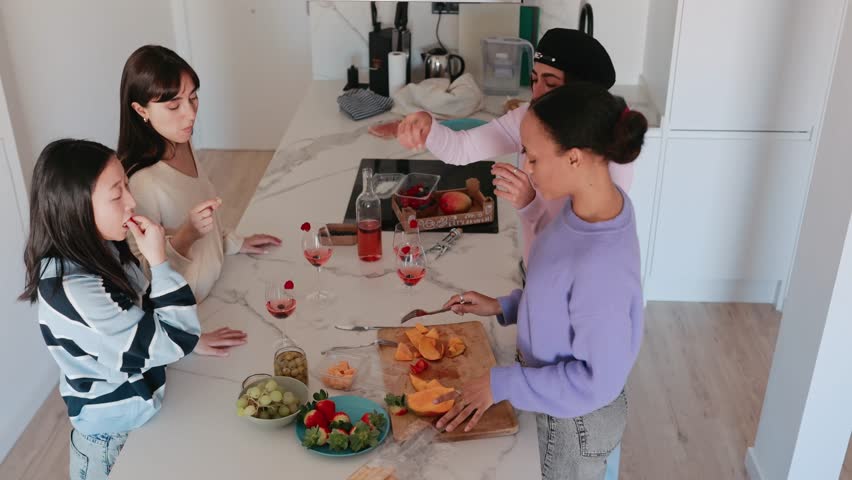 Group of four female friends standing at a table eating while talking
