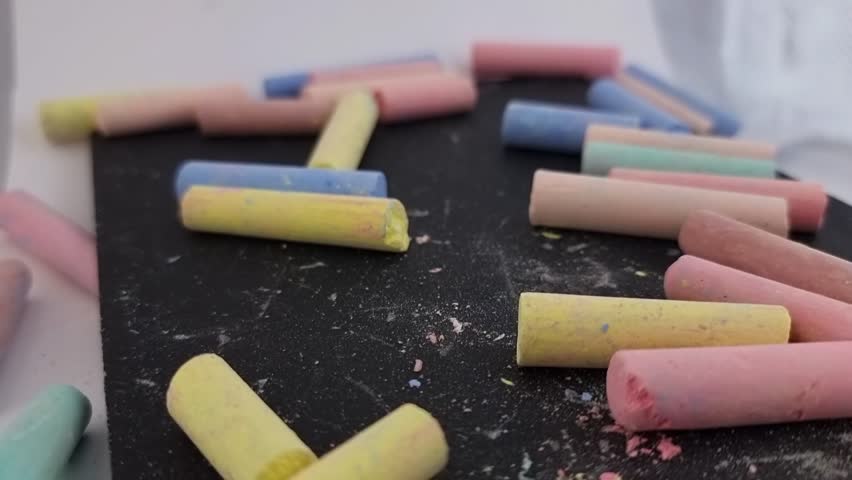 Colorful chalk pieces on blackboard, creative art supplies