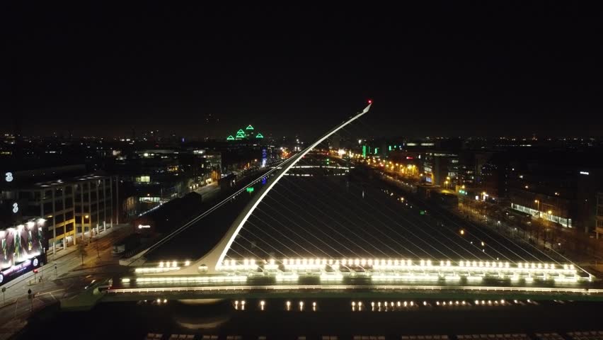 Night aerial of a lit cable-stayed bridge over a river.