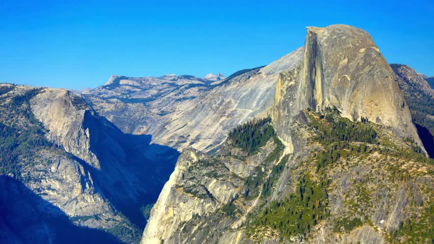Majestic granite cliffs of Yosemite National Park rising above lush valleys, showcasing dramatic rock formations, wilderness and iconic natural scenery.